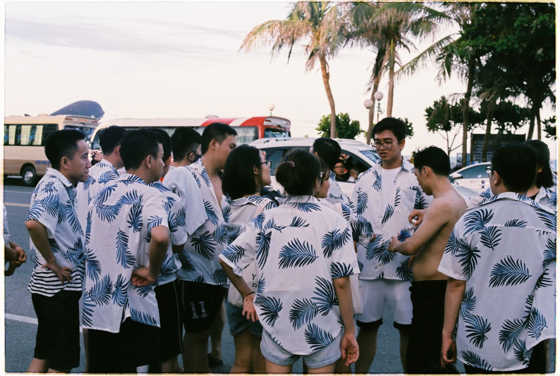A group of people in matching outfits gathers on a city street during summer.
